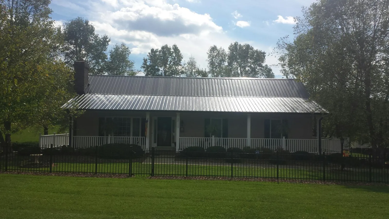 Gray metal roof on a brick ranch with a full width front porch — Gutter Guard Installation work by our crew in Bethany